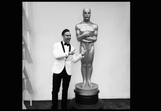 Matthew Rodrigues posant à côté de la Statue « oversize » des Oscars