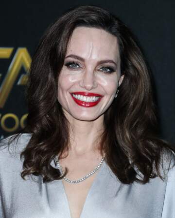 Angelina Jolie très souriante avec une beau rouge à lèvres rouge et une robe argentée