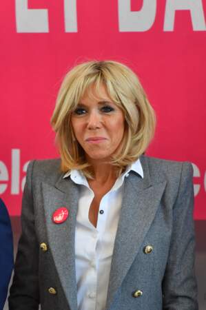 Brigitte Macron, chemise blanche ouverte et blazer gris pour sa dictée