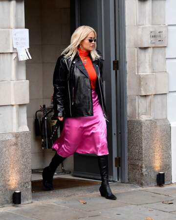 Rita Ora casse son look en satin acidulé avec une paire de santiags noires, assorties à son perfecto.