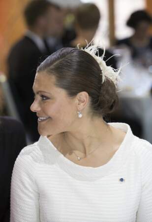 Cheveux plaqués à l'excès pour Victoria de Suède qui modernise son chignon avec un ornement en plumes blanches