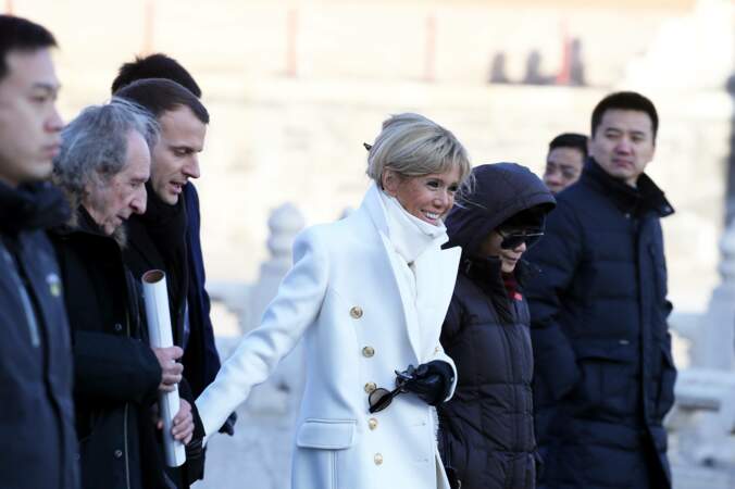 Brigitte Macron très chic avec son manteau blanc et son sac à mains, tous deux signés Balmain