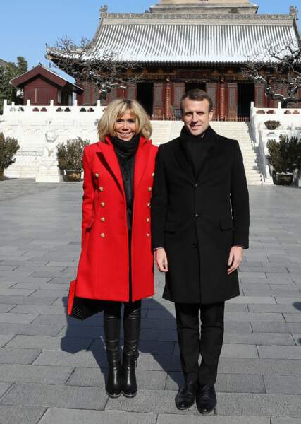 Brigitte Macron porte des bottines et un sac noirs tous deux signés Christian Louboutin