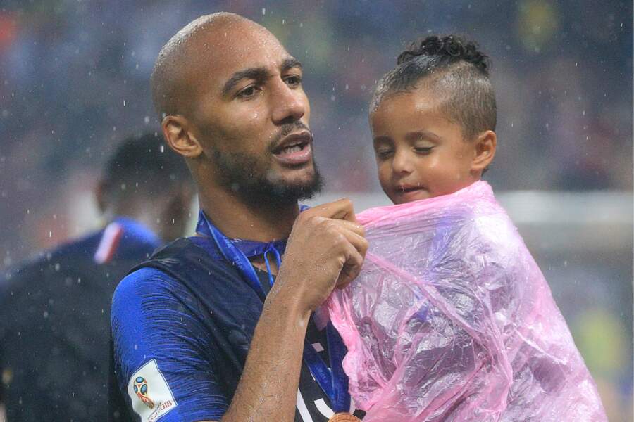 Steven Nzonzi protège tant bien que mal sa fille de la pluie, après la victoire des Bleus à la Coupe du monde