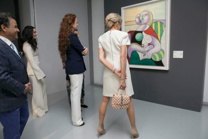 Brigitte Macron en robe blanche, avec escarpins et sac Louis Vuitton