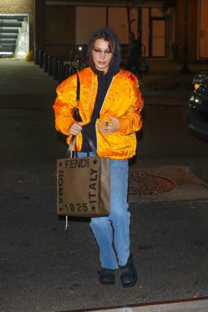 Bella Hadid nous inspire un look streetwear : sweat à capuche sur bomber flashy.