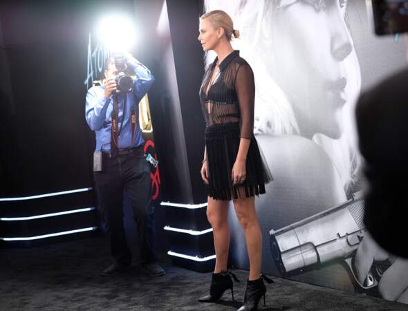 Charlize Theron : en jupe courte et soutien-gorge griffé apparant