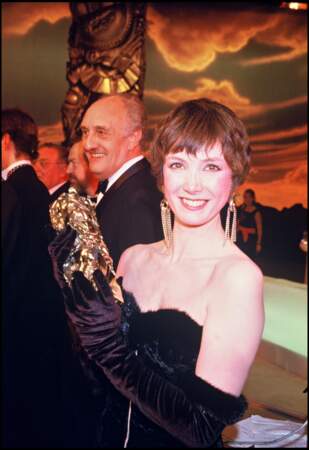 Sabine Azéma, en robe fourreau bustier pose avec son césar pour "Un Dimanche à la Campagne", en 1985