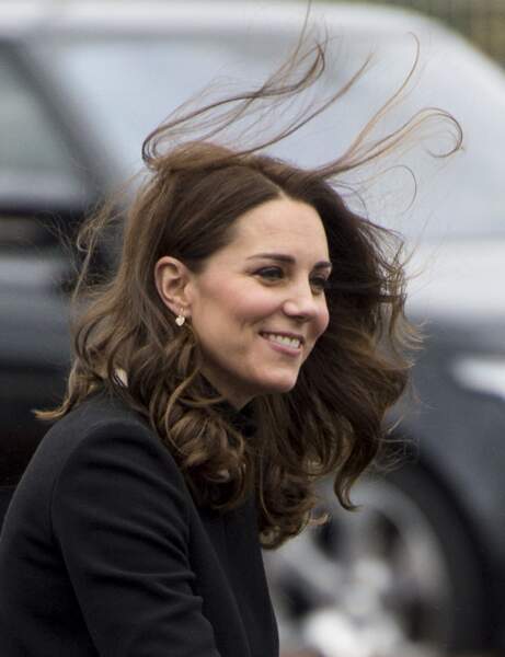 Très souriante, Kate Middleton, les cheveux au vent et des boucles d'oreille en forme de cœur
