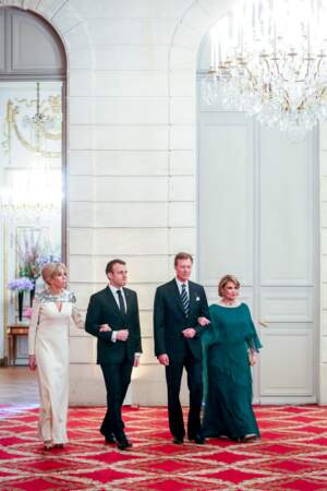 Brigitte Macron en robe longue blanc crème à sequins et son joli chignon sophistiqué