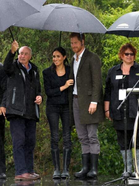 En Nouvelle-Zélande, Meghan Markle enceinte se protège de la pluie avec le prince Harry.