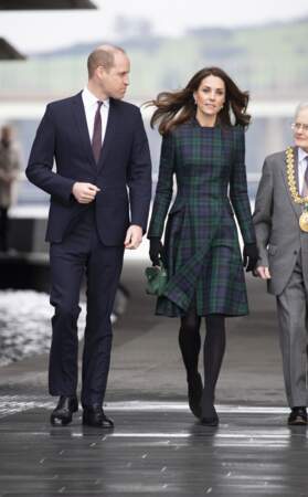 En Ecosse, Kate Middleton est vêtue d'un manteau, comme une robe, à tartan, accessoirisé d'un sac malle vert. 