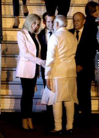 Brigitte Macron, très sophistiqué à son arrivée en Inde, en escarpins et pantalons noir et veste rose pâle en satin