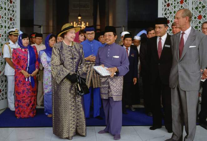 Dans son long manteau-caftan, la reine reçoit l'hommage d'un dignitaire musulman malaisien