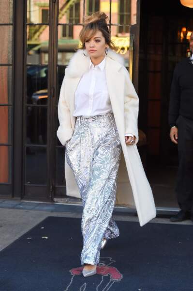 Rita Ora en pantalon lamé argent et manteau long blanc Max Mara le 7 décembre 2017 à New York
