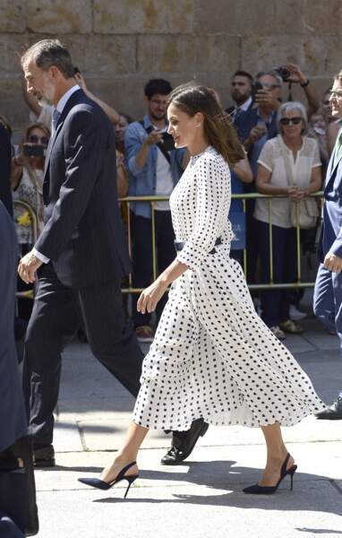 La robe blanche à pois noirs de la reine Letizia d'Espagne est accessoirisée d'escarpins et d'une ceinture noirs.