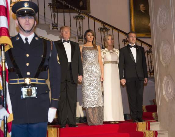Brigitte Macron en robe de vestale blanche et dorée Louis Vuitton avec Melania Trump le 24 avril 2018