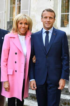 Brigitte Macron opte pour un caban de couleur rose pour sortir de la monotonie cette saison.