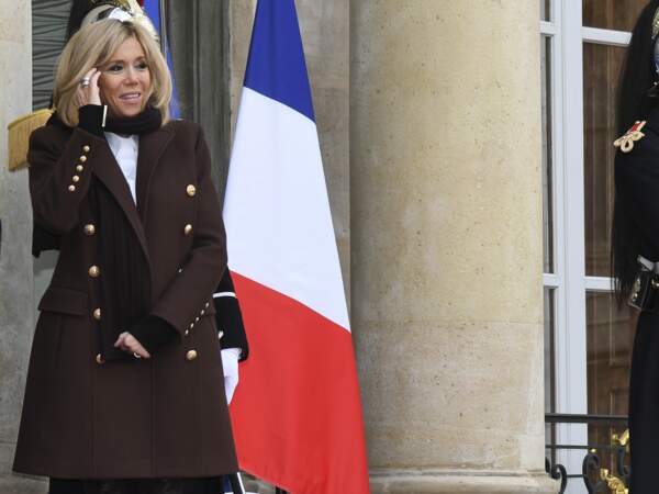 Brigitte Macron en long manteau aux boutons dorés