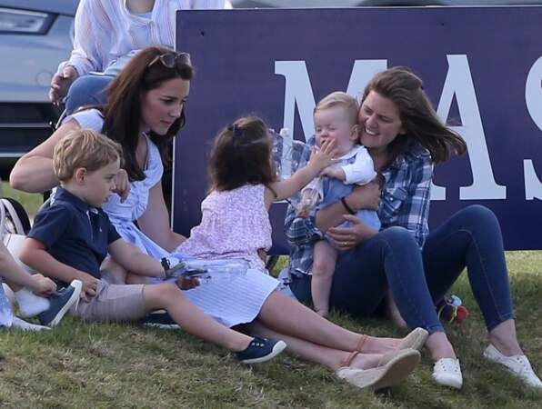 La princesse Charlotte mettant une main sur la bouche du bébé en face d'elle
