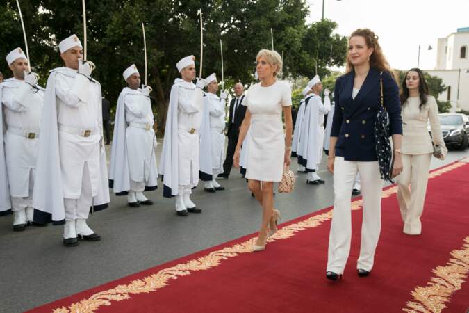 Brigitte Macron en robe blanche Louis Vuitton, avec escarpins et sac Louis Vuitton au côté de Lalla Salma