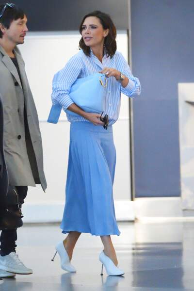 Victoria Beckham, souriante et toute de bleu vêtue, arrive à l'aéroport de New York.