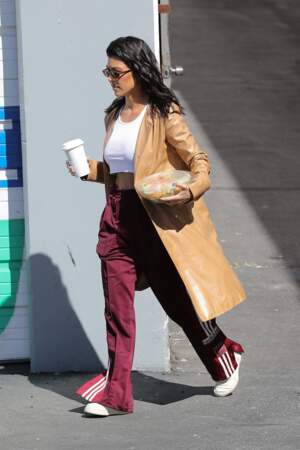 Kourtney Kardashian en mode sportswear avec un trench camel vinyle et brillant.