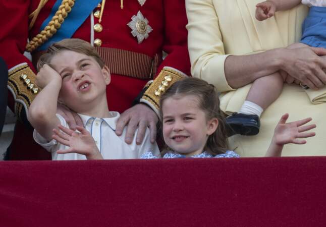 Le prince George se tenant la tête et la princesse Charlotte écartant les bras