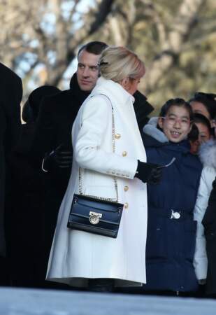 Brigitte Macron très chic avec son manteau blanc et son sac à mains, tous deux signés Balmain