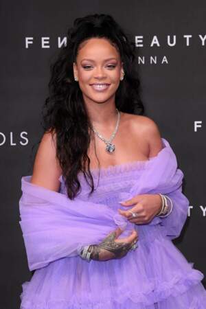 Rihanna très souriante en robe violette et queue-de-cheval wavy