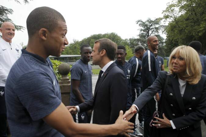 Brigitte Macron en blazer et jean slim serre la main de Kilian Mbappé