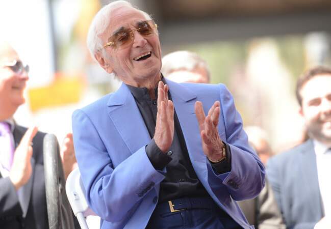 L'immense Charles Aznavour, élégant en costume bleu roi et lunettes de soleil.