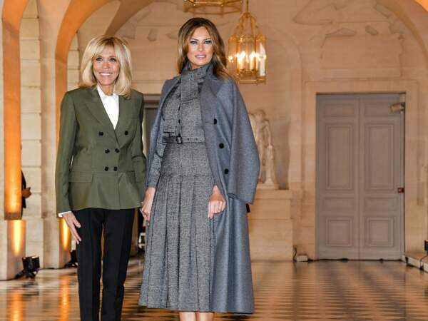 Avec Brigitte MAcron, Melania Trump ose le total look gris, manteau long posé sur les épaules.