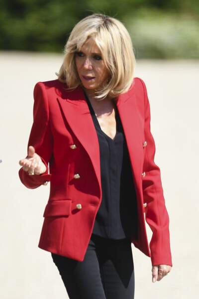 Brigitte Macron en veste militaire rouge et jean noir