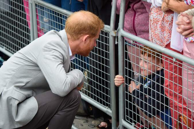 Le prince Harry, prend soin d'un enfant venu le voir lors de son voyage à Dublin avec Meghan Markle, le 11 juillet 