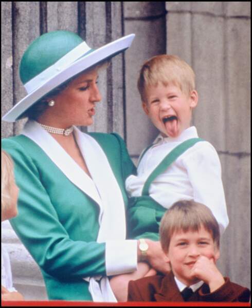 Harry fait une grimace dans les bras de Diana, à côté de William, lors de la parade "Trooping The Colour" en 1988