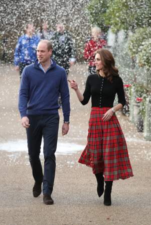 Kate Middleton en rouge et noir entre jupe écossaise, bottes et top noirs