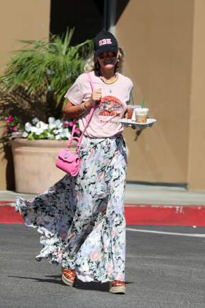 Laeticia Hallyday mixe t-shirt rose pâle avec une jupe volantée et un sac flashy.