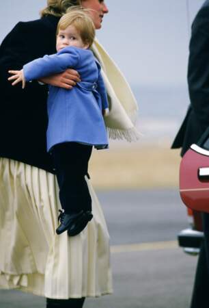 A l'aéroport d'Aberdeen, la princesse Diana agrippe son petit dernier, interloqué par les photographes