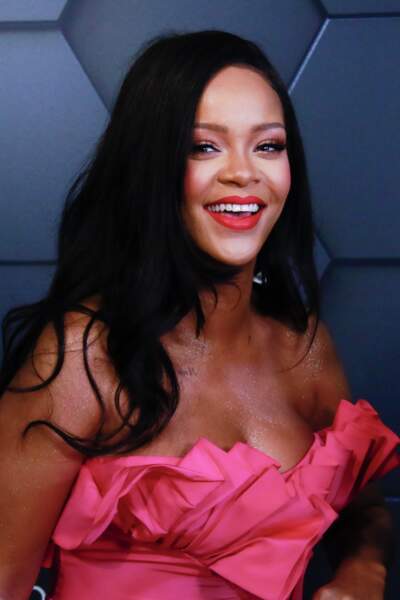 Rihanna rayonnante avec un rouge assorti à sa robe et la peau irisée de paillettes