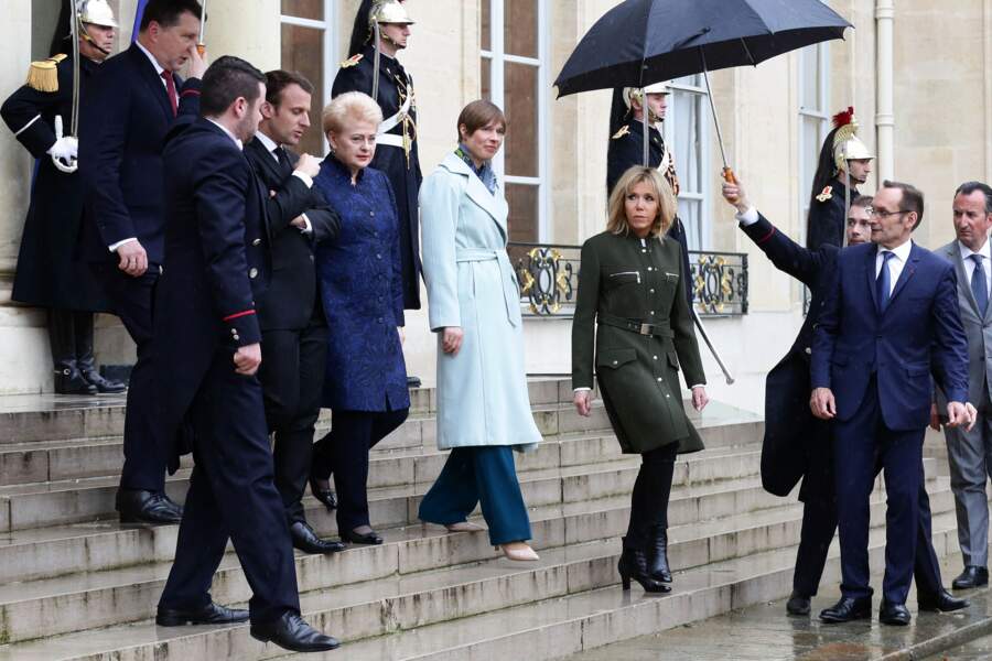 Brigitte Macron en manteau d'officier Louis Vuitton et bottines à talons