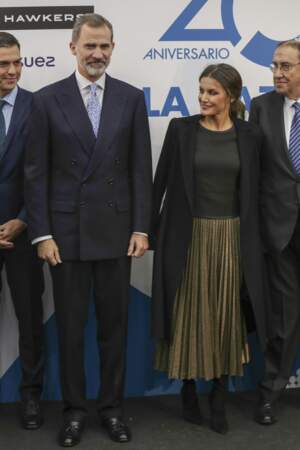 La jupe dorée de Letizia d'Espagne est portée avec des talons mats noirs et une veste noire portée sur les épaules.