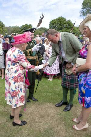La reine Elizabeth II salue l'un des convives de la garden party du palais de Holyroodhouse à Edimbourg