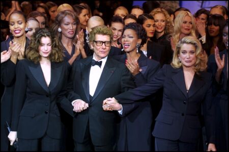 En 2002, le dernier défilé de Mr Saint Laurent entouré de ses muses en smoking, Laetitia Casta et Catherine Deneuve