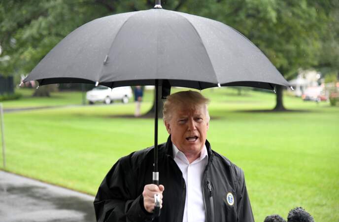 Donald Trump sous son parapluie parlant à des journalistes près de la Maison Blanche