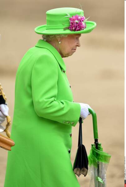 Elizabeth II en vert pomme. Décidément,  cette couleur qui ne sied à personne lui va comme un gant ! A noter : le parapluie coordonné. 