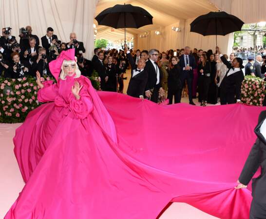 Lady Gaga fait virevolter sa robe si longue qu'on doit l'aider pour tenir la traîne