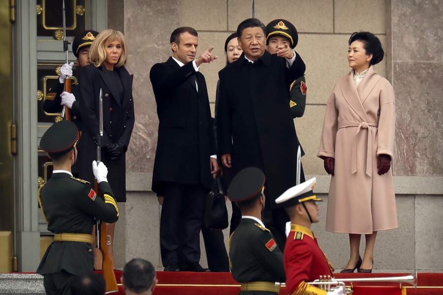 Brigitte Macron a opté pour un manteau noir aux boutons rouges, une robe noire et une paire de gants noirs face à Lady Peng Liyuan, la première dame chinoise