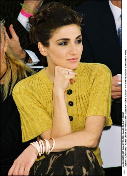 2004 : Sublime, Julie Gayet a les cheveux bruns et adopte un chignon relevé et frisé. L'actrice est sophistiquée pour se rendre au défilé Louis Vuitton.