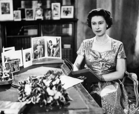 25 décembre 1957 : La Reine Elizabeth II est prise en photo au sein de la grande bibliothèque de Sandringham pour le jour de Noël.  